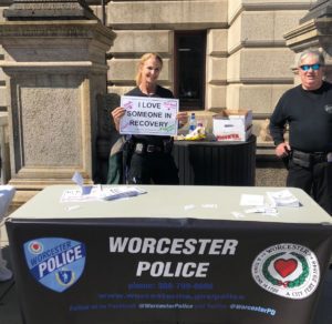 Woman holding sign behind a table at Worcester Police CPAR Event